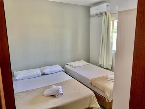 2 camas en una habitación pequeña con ventana en Vila do Rosa, en Praia do Rosa