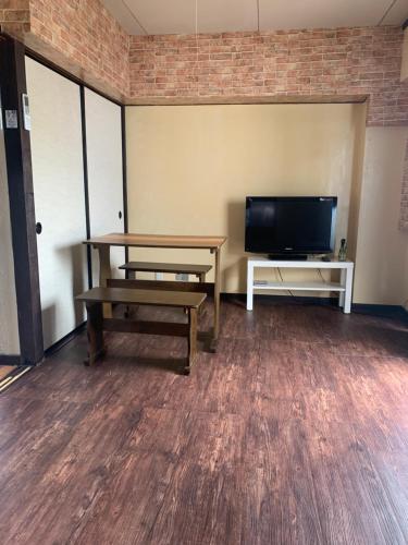 a room with a table and a flat screen tv at 山下ホテル305 in Kurosakimachi