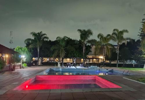 ein Schwimmbad mit roten Lichtern in einem Park in der Nacht in der Unterkunft HOTEL SAN MARCOS in Aguascalientes