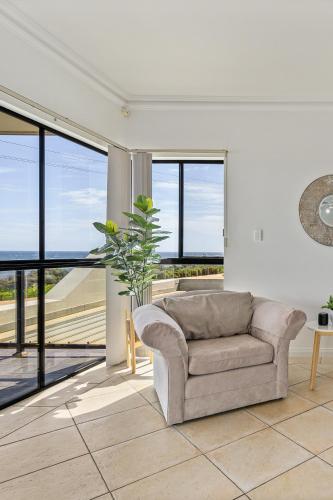 a living room with a couch and large windows at Mareblue Villa - Aldinga Beach - C21 SouthCoast Holidays in Aldinga Beach