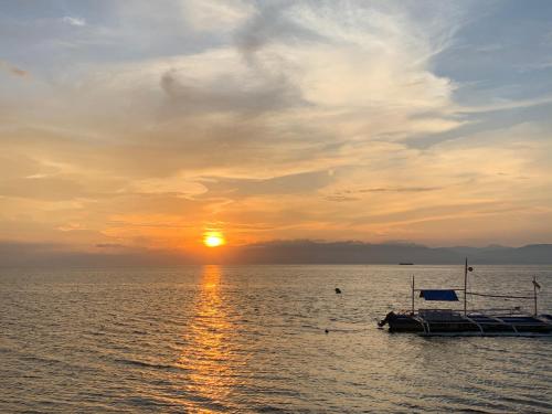 a boat in the water with the sunset in the background at Coconut Inn Moalboal in Moalboal