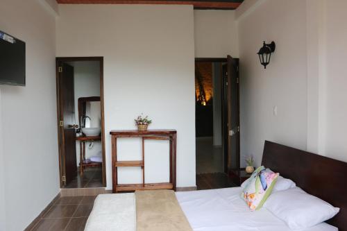 a bedroom with a bed with white sheets and a lamp at MANIPURA in Guaduas