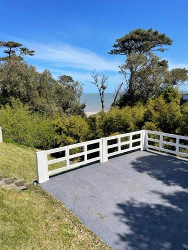 a white fence and a driveway with the ocean in the background at Costa Villa in Atlántida