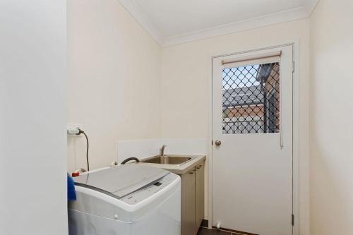 a white laundry room with a sink and a washing machine at The Summer House ~ 2 blocks to Beach in Apollo Bay