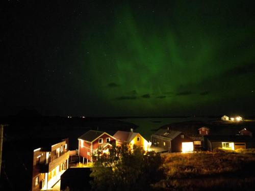 a group of houses under the green northern lights at Rorsundet Brygge in Vega