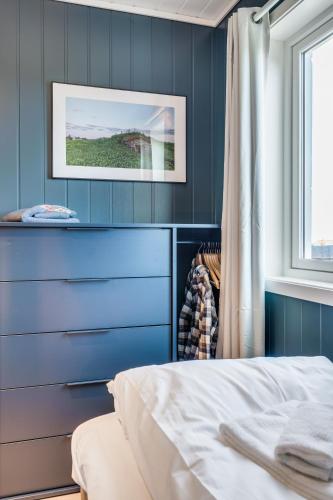 a bedroom with blue walls and a bed and a window at Rorsundet Brygge in Vega