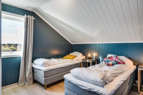 two beds in a room with blue walls and a window at Rorsundet Brygge in Vega
