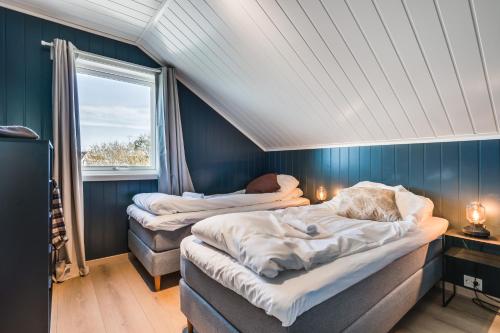 two beds in a room with blue walls and a window at Rorsundet Brygge in Vega