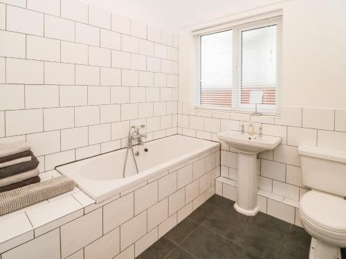 a white bathroom with a tub and a sink at Hafan Y Mor in Rhos-on-Sea
