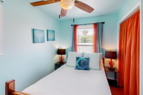 a bedroom with a bed and a window with orange curtains at Down By The Sea in Port Aransas