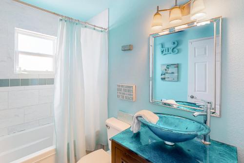 a blue bathroom with a sink and a mirror at Down By The Sea in Port Aransas