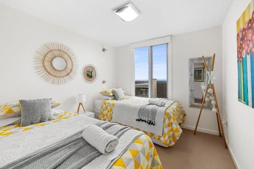 a bedroom with two beds and a mirror on the wall at Point Grey Apartment 2 in Lorne
