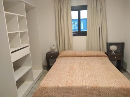 ein Schlafzimmer mit einem Bett, einem Fenster und Regalen in der Unterkunft Alquiler DIARIO hasta 4 personas in Tandil