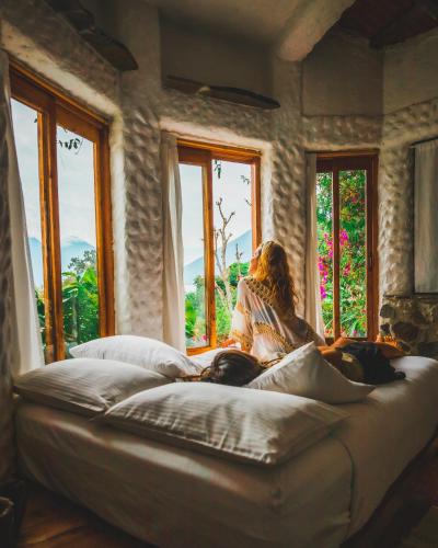 a woman sitting on a couch looking out the window at Lush Atitlán in San Marcos La Laguna
