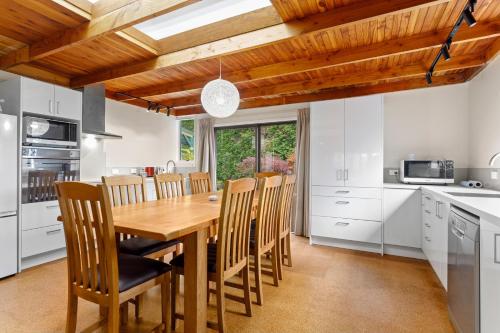 a kitchen with a wooden dining table and chairs at Garden House in Opotiki