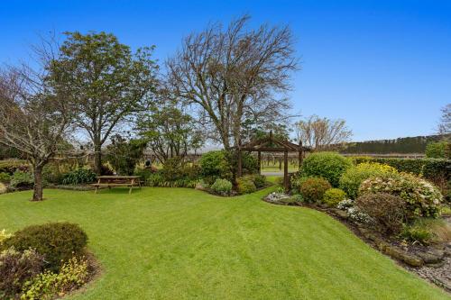 a garden with a bench and a gazebo at Garden House in Opotiki