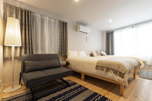 a bedroom with a bed and a chair and a window at SAKURA INN Asakusa station walking 4 Min Shinjuku Shibuya Ginza Oshiage in Tokyo