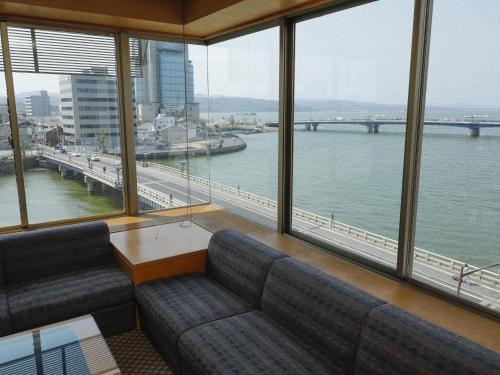 a room with a couch and a view of the water at Ohashikan in Matsue
