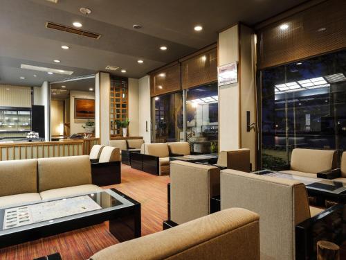 a waiting room with couches and tables and windows at Ohashikan in Matsue