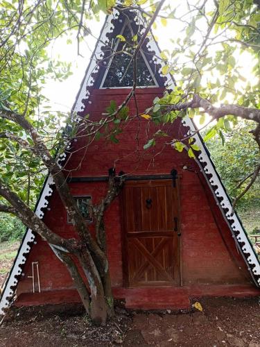 a red barn with a door and a tree at Porsu in Canacona