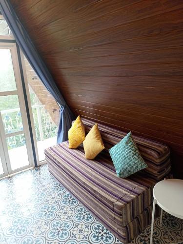 a bed with yellow and green pillows in a room at Porsu in Canacona