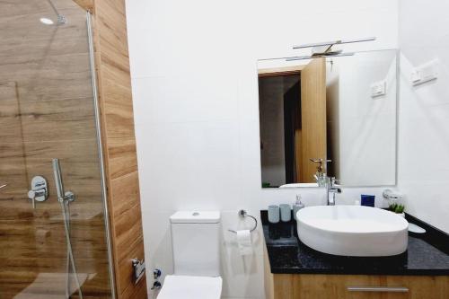 a white bathroom with a sink and a shower at Apartamento encantador com piscina e vista mar in Praia