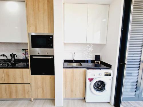 a kitchen with a washing machine and a washer at Apartamento encantador com piscina e vista mar in Praia