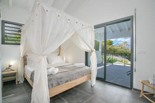 a bedroom with a canopy bed and a balcony at VILLA 55°AOC in Grande Anse