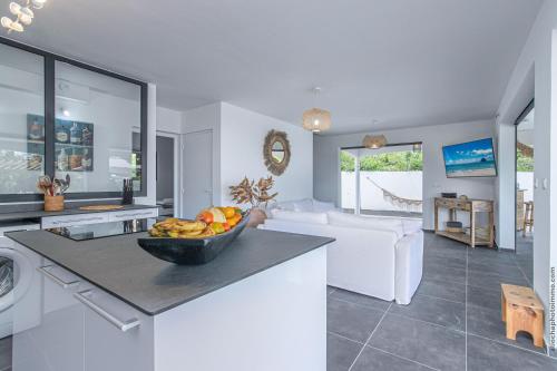 a kitchen and living room with a bowl of fruit on a counter at VILLA 55°AOC in Grande Anse