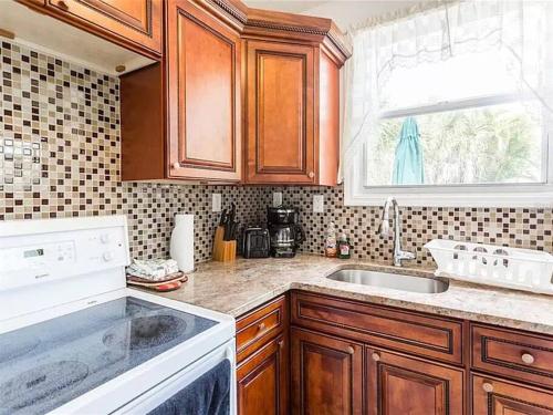 a kitchen with wooden cabinets and a sink and a window at Charming Studio Unit Across from Lido Key Beach in Sarasota