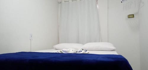 1 cama con manta azul y 2 almohadas en Espaço completo bem localizado c estacionamento, en Foz do Iguaçu