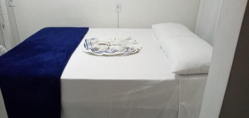a white bed with a blue blanket on it at Espaço completo bem localizado c estacionamento in Foz do Iguaçu
