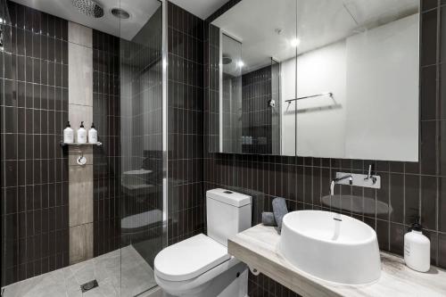 y baño con aseo, lavabo y espejo. en Luxuria Apartments - Fulton Lane, en Melbourne