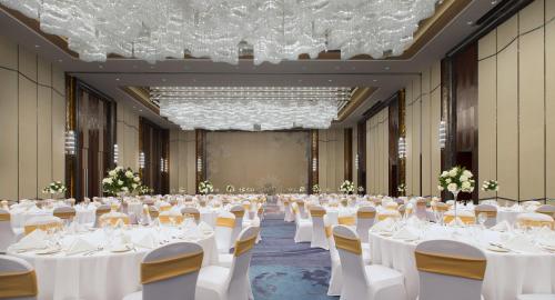 a large banquet hall with white tables and chairs at Pullman Yantai Center in Yantai