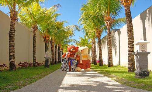 two large teddy bears are standing on a sidewalk between palm trees at Vivara Bali Private Pool Villas & Spa Retreat in Jimbaran