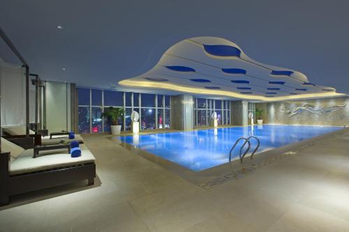 a large swimming pool in a building with a large building at Pullman Yantai Center in Yantai