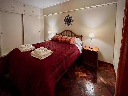 1 dormitorio con 1 cama roja y 2 toallas en El Carnaval Apart Jujuy en San Salvador de Jujuy