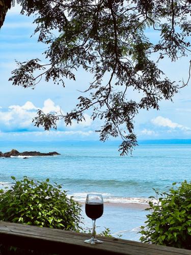 a glass of wine sitting on a table near the beach at Choibana Ecolodge in Bahía Solano