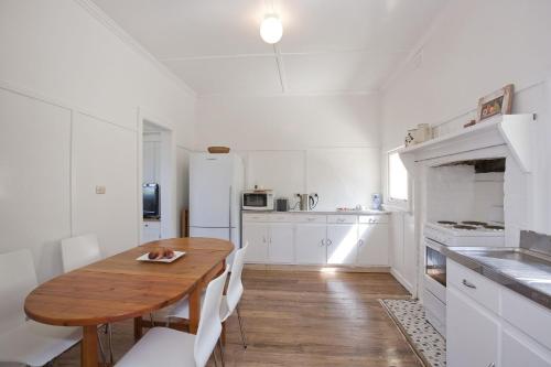 a kitchen with a wooden table and white cabinets at Salamanca in Lorne
