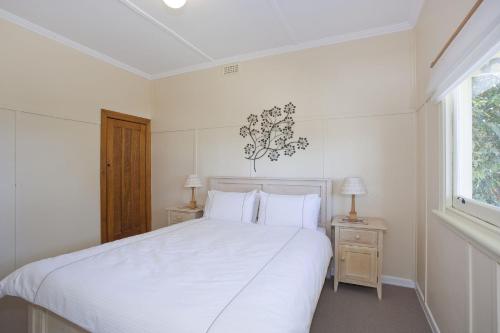 a white bedroom with a large bed and two night stands at Salamanca in Lorne