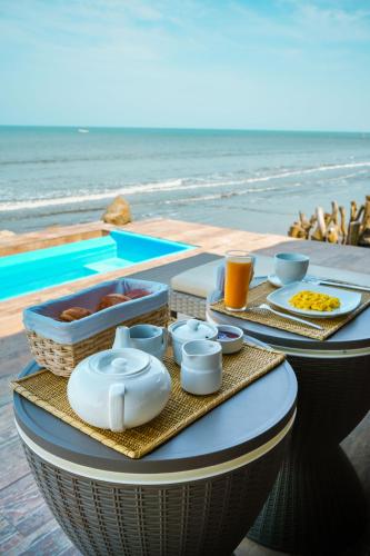 a table with food and drinks next to the beach at Hotel Boutique Beso de Sal in Colán