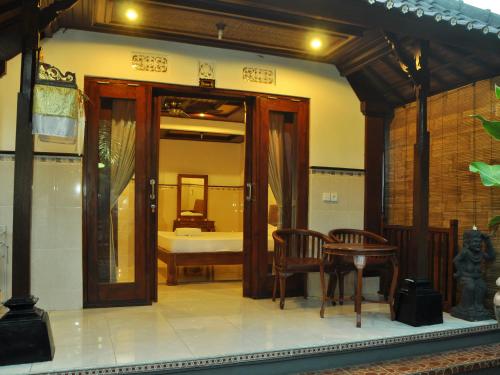 una camera con una porta, un tavolo e un letto di Dewi Antara Homestay ad Ubud