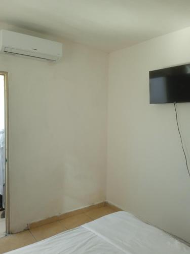 a white room with a bed and a tv on a wall at Santa Rosa 4Rest in Monterrey