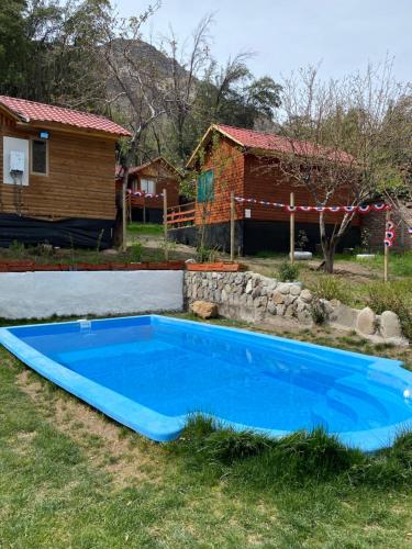 a blue swimming pool in front of a house at Cabañas Between Hills in San Alfonso