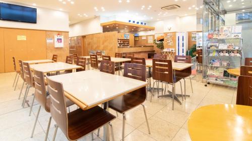 Toyoko Inn Hokkaido Tomakomai Ekimae في توماكوماي: غرفة طعام مع طاولات وكراسي في متجر
