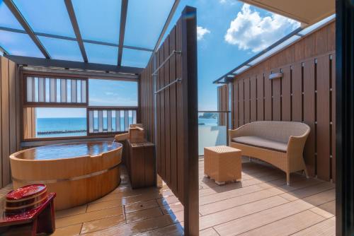 a tub in a room with a view of the ocean at Isoaruki no Yuyado Ushiogumo -6 years or older- in Kawazu