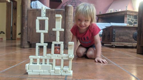 a young child playing with a wooden block tower at Hostal Tribu Malinalco in Malinalco