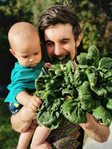 a man holding a baby and a bunch of spinach at Hostal Tribu Malinalco in Malinalco