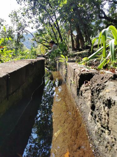 a man is sitting on the side of a river at Hostal Tribu Malinalco in Malinalco