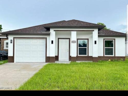 a house with a garage and a green lawn at Home Sweet Home in Fort Myers